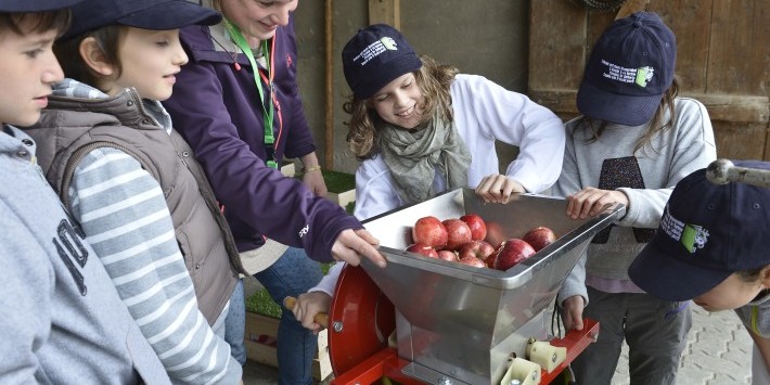 Eine Gruppe von Kinder machen zusammen Apfelmost.