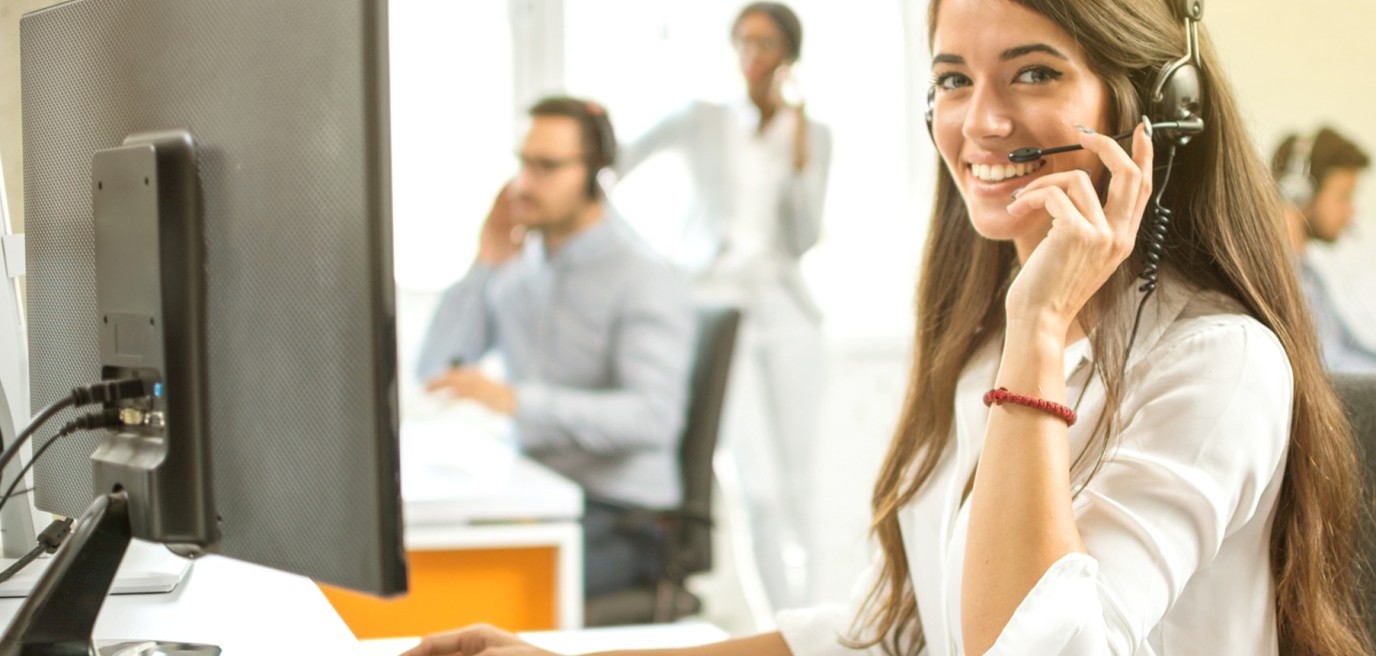 Eine lächelnde Frau sitzt im Büro vor dem Computer